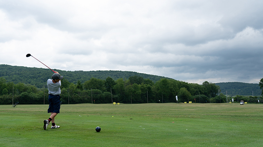 A young golfer swinging a club at the Practice Facility. 